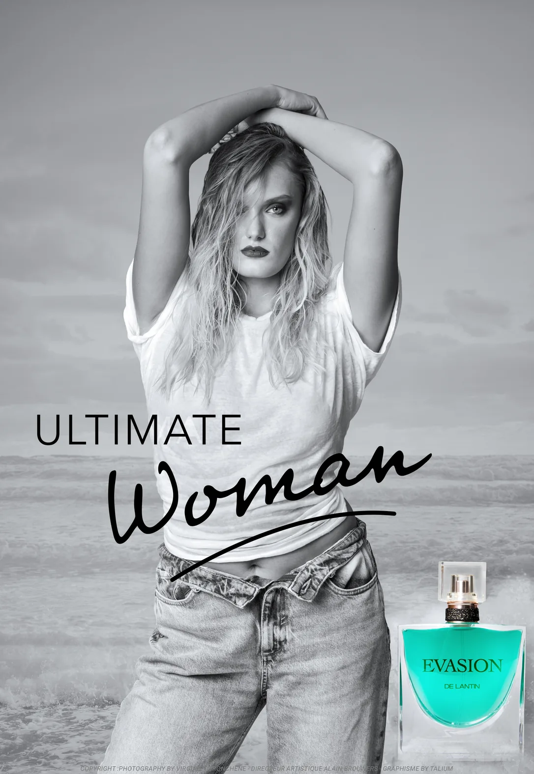 Affiche : en noir et blanc, une jeune femme aux cheveux mouillés, les bras levés au-dessus de la tête, se tient face à la mer dans un T-shirt blanc et un jean. Un flacon turquoise s'allume en bas à droite. Titre : Ultimate Woman.